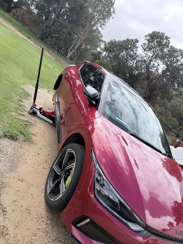 Red Kia jacked up for a puncture repair at a roadside call-out in Perth